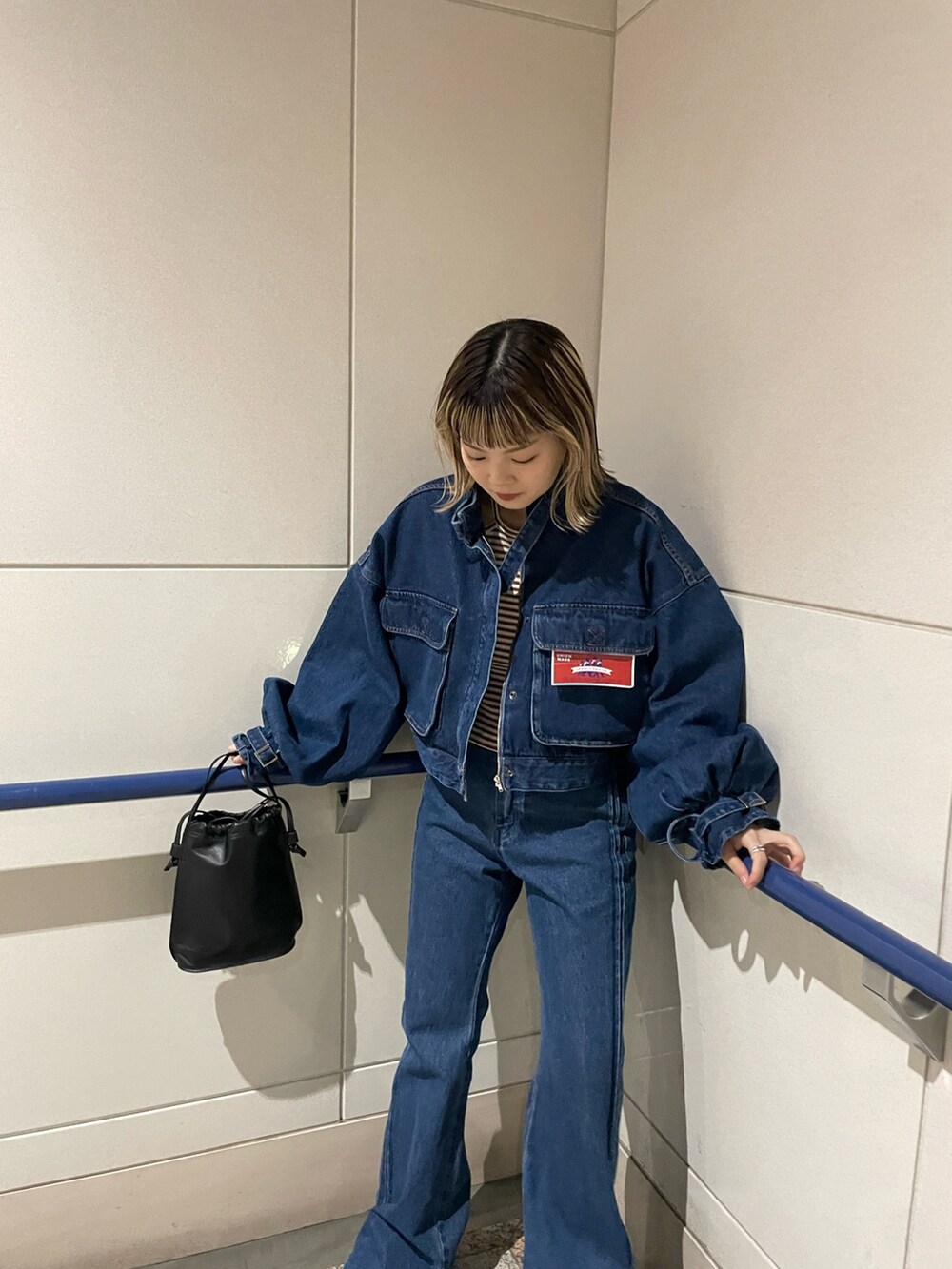 ブルー系のデニムパンツ、ブルー系のデニムジャケット、ブラウン系のTシャツ/カットソーを着用したレディースの秋コーディネートの2枚目の写真