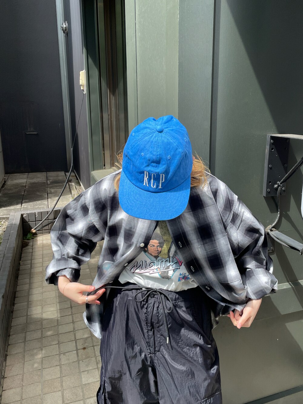 ブラック系のカーゴパンツ、ブラック系のシャツ/ブラウス、ブルー系のキャップを着用したレディースの春コーディネートの3枚目の写真