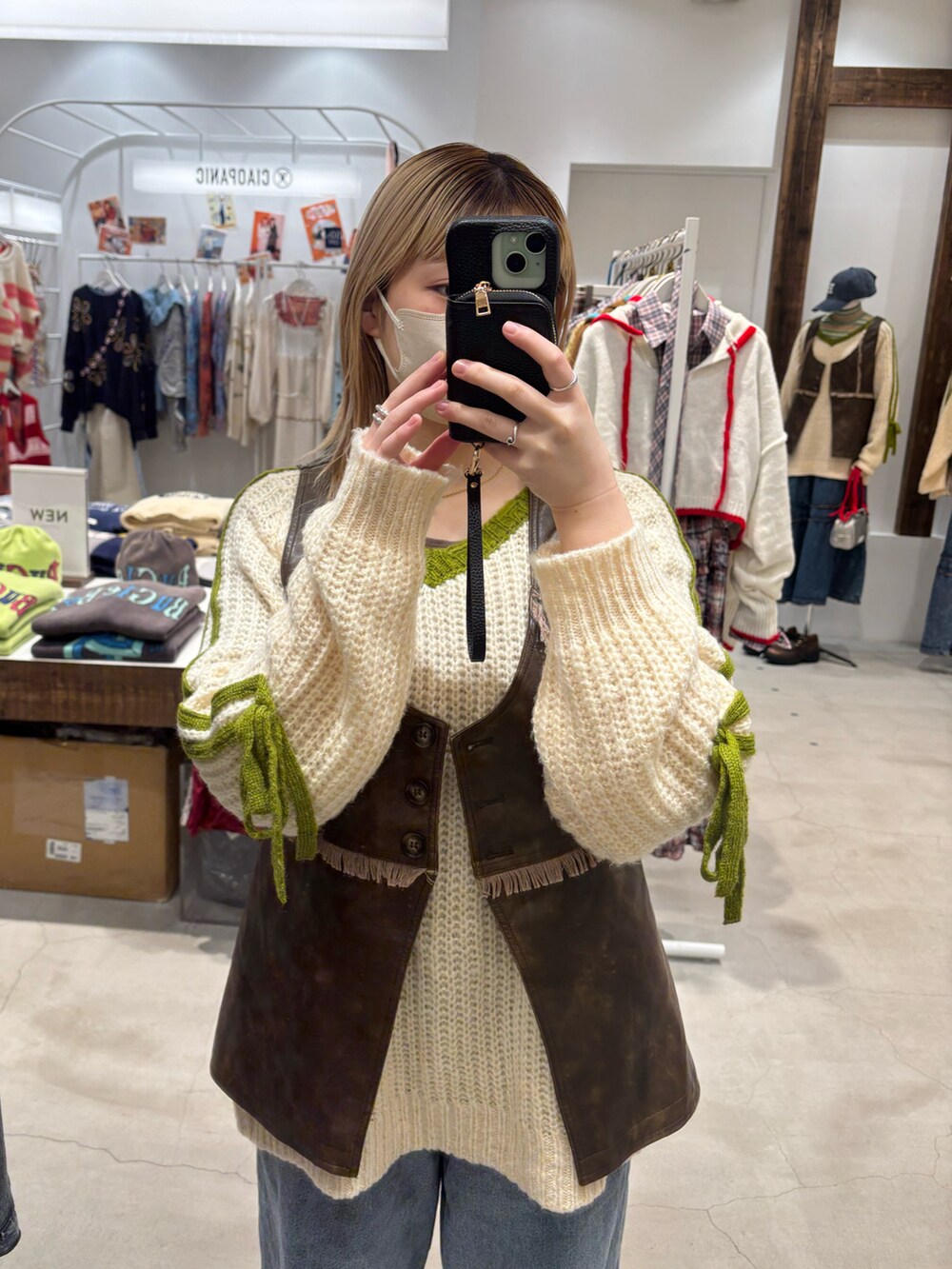 ブラウン系のベスト、ブルー系のデニムパンツ、ベージュ系のニット/セーターを着用したレディースの冬コーディネートの3枚目の写真