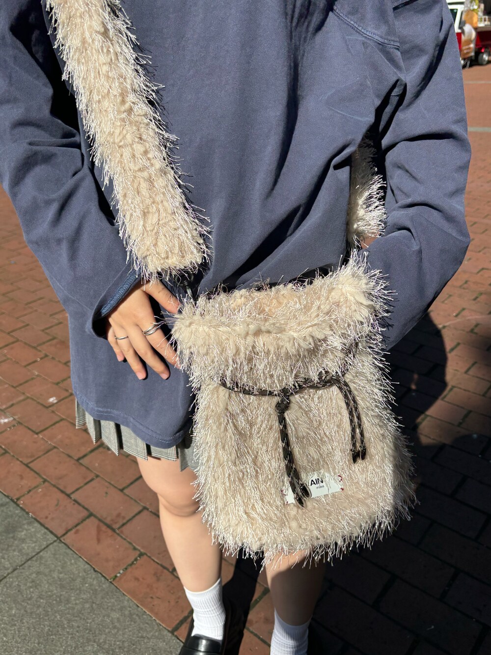 ブルー系のTシャツ/カットソー、ベージュ系のショルダーバッグ、グレー系のスカートを着用したレディースの秋コーディネートの4枚目の写真