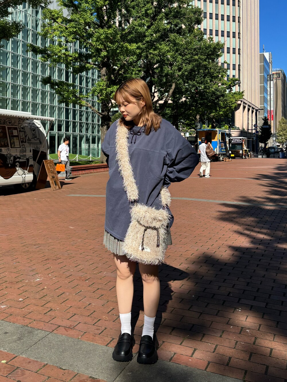 ブルー系のTシャツ/カットソー、ベージュ系のショルダーバッグ、グレー系のスカートを着用したレディースの秋コーディネートの2枚目の写真