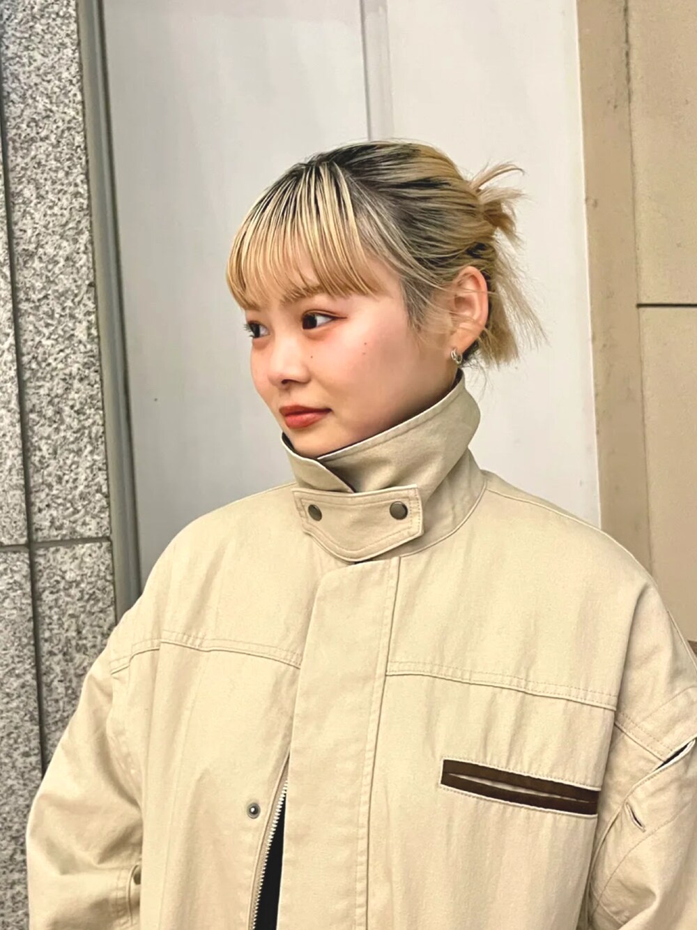 ベージュ系のステンカラーコートを着用したレディースの春コーディネートの2枚目の写真