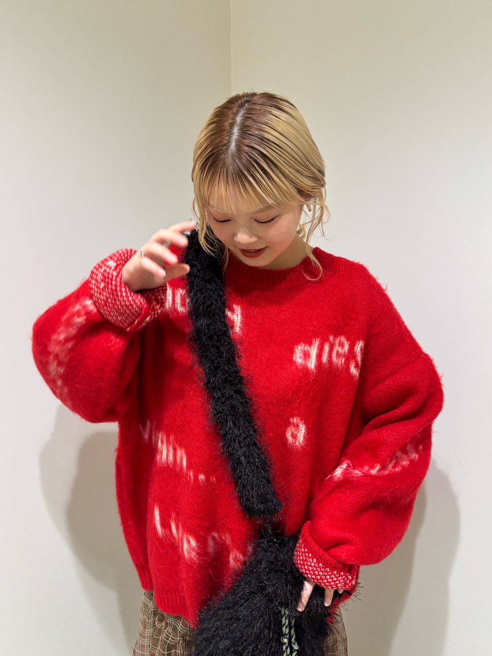 レッド系のニット/セーター、ブラック系のショルダーバッグ、ブラウン系のスカートを着用したレディースの冬コーディネートの4枚目の写真