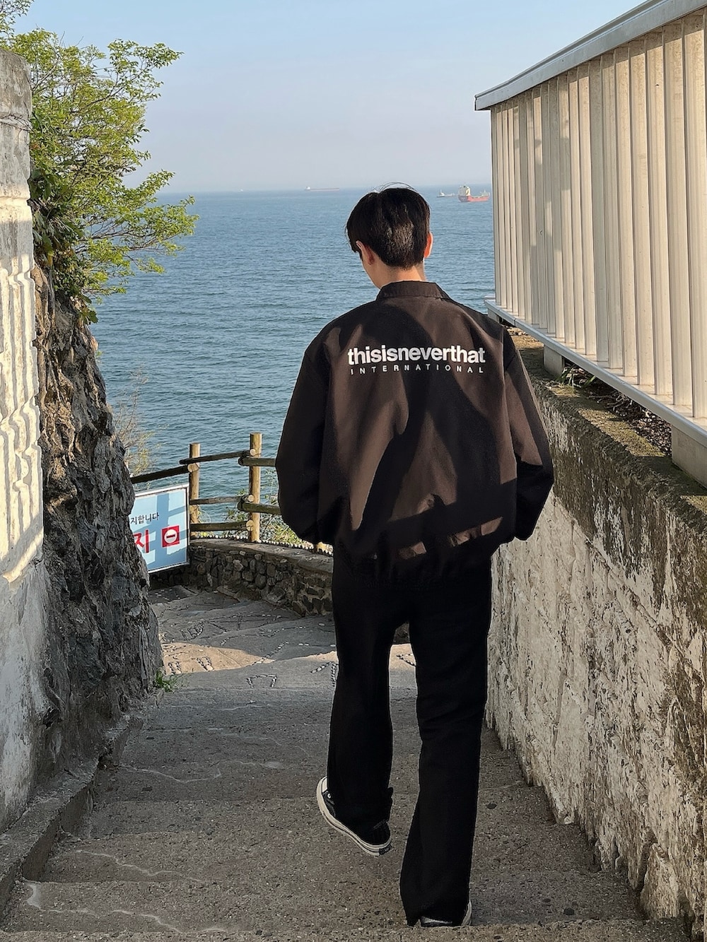 ブラック系のブルゾン、ブラック系のボディバッグ/ウエストポーチ、ブラック系のスニーカーを着用したメンズの春コーディネートの2枚目の写真