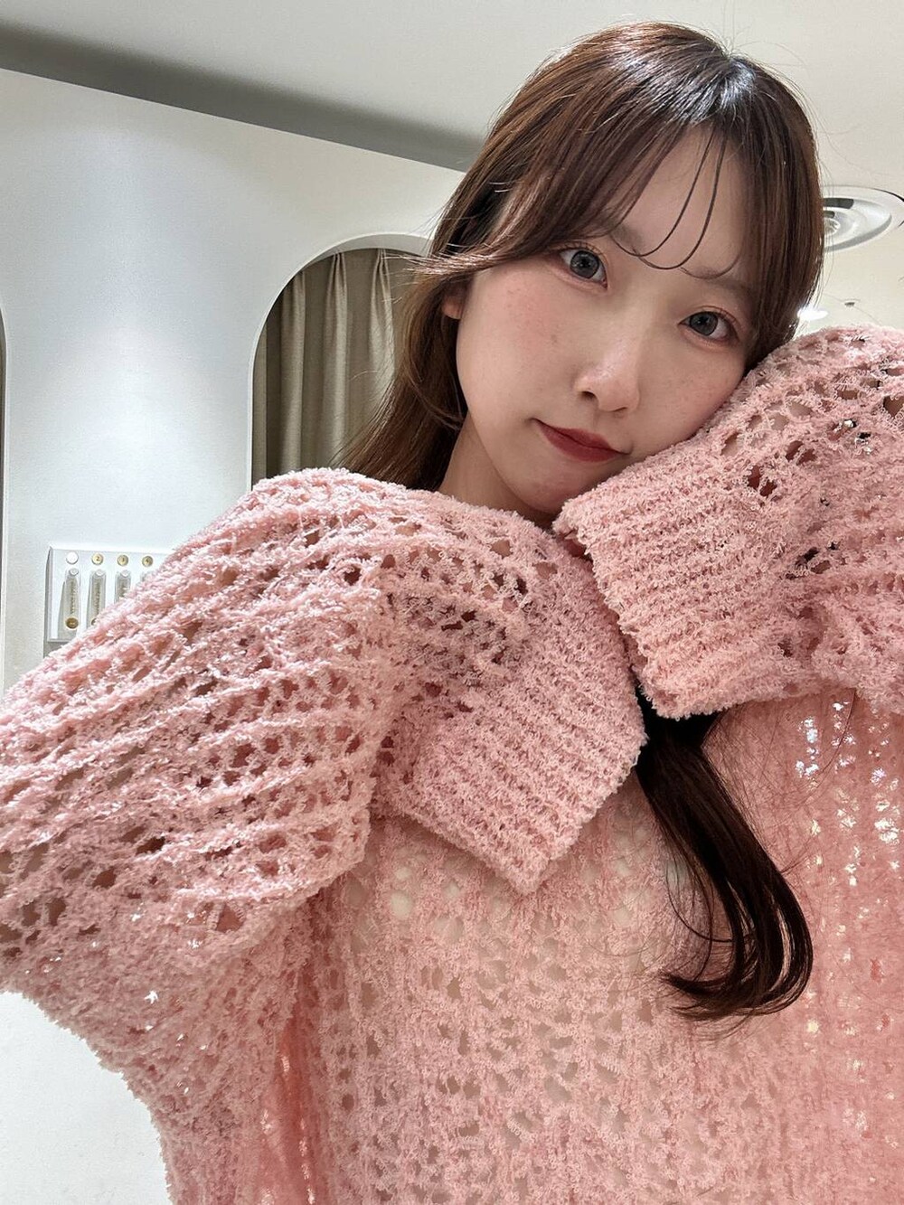 ブラック系のパンプス、ピンク系のニット/セーター、ホワイト系のスカートを着用したレディースの冬コーディネートの2枚目の写真