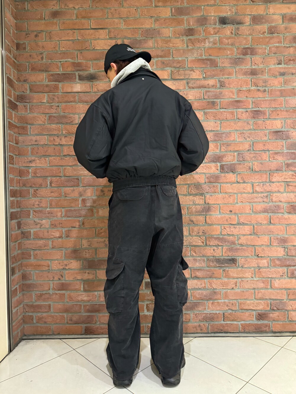 グレー系のパーカー、ブラック系のブルゾン、ブラック系のカーゴパンツを着用したメンズの秋コーディネートの2枚目の写真
