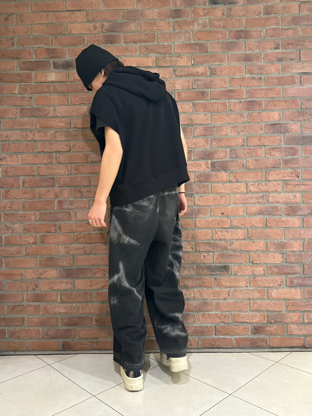 ブラック系のパーカー、ブラック系のシューズ、ブラック系のデニムパンツを着用したメンズの春コーディネートの2枚目の写真