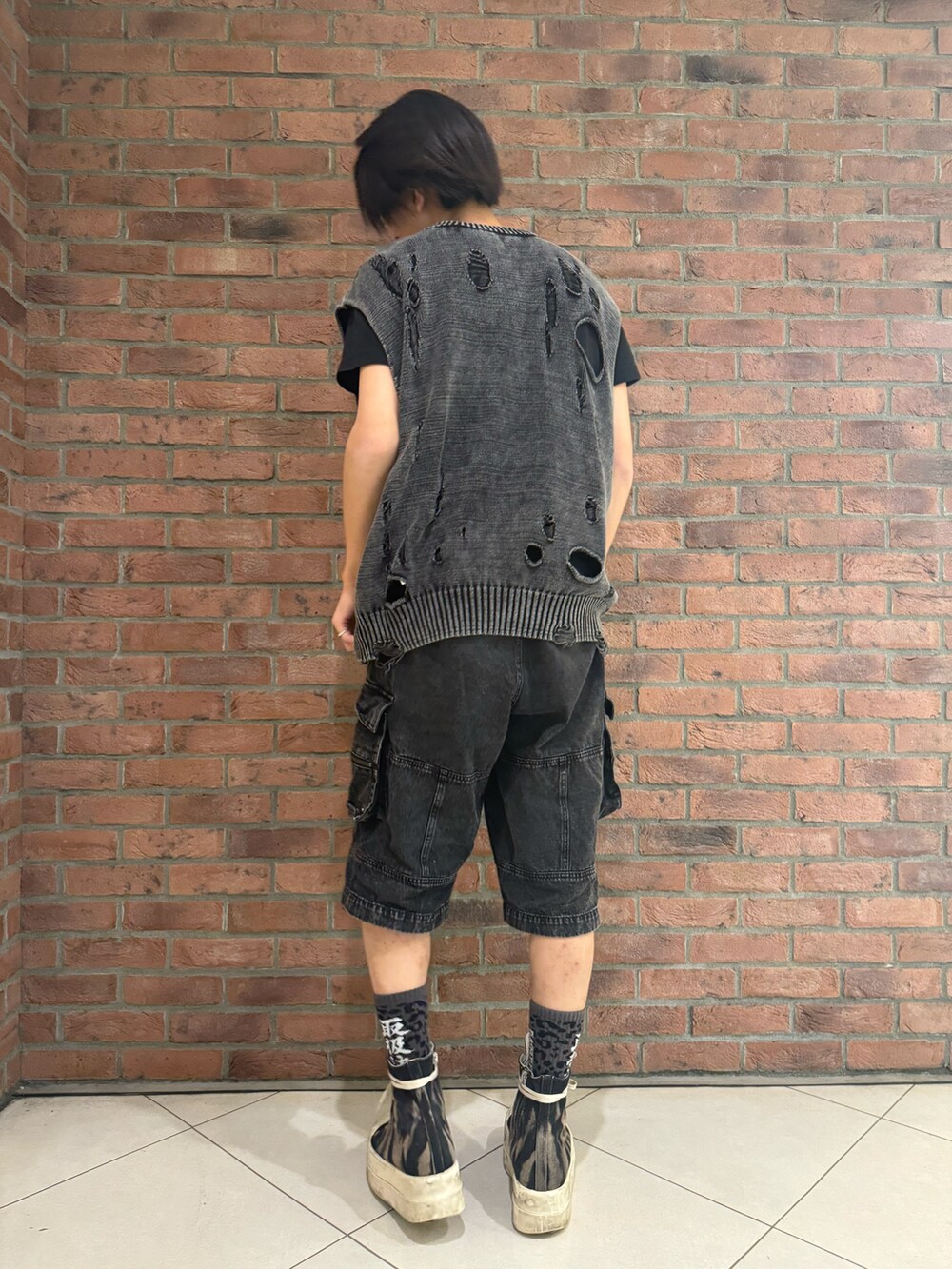 ブラック系のニット/セーター、ブラック系のデニムパンツ、ブラック系のシューズを着用したメンズの春コーディネートの2枚目の写真