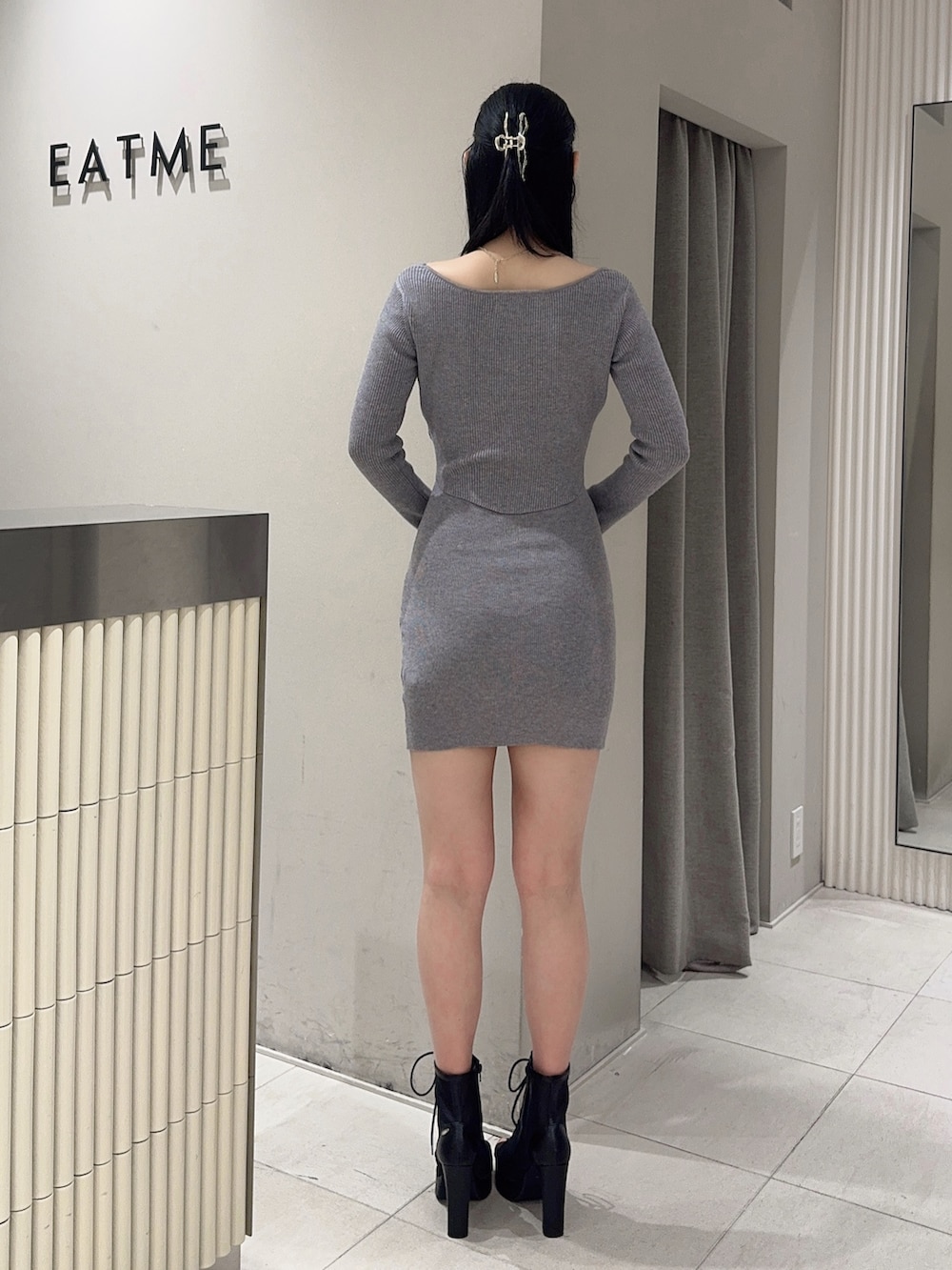 グレー系のワンピース、ブラック系のブーツ、ブラック系のハンドバッグを着用したレディースの冬コーディネートの4枚目の写真