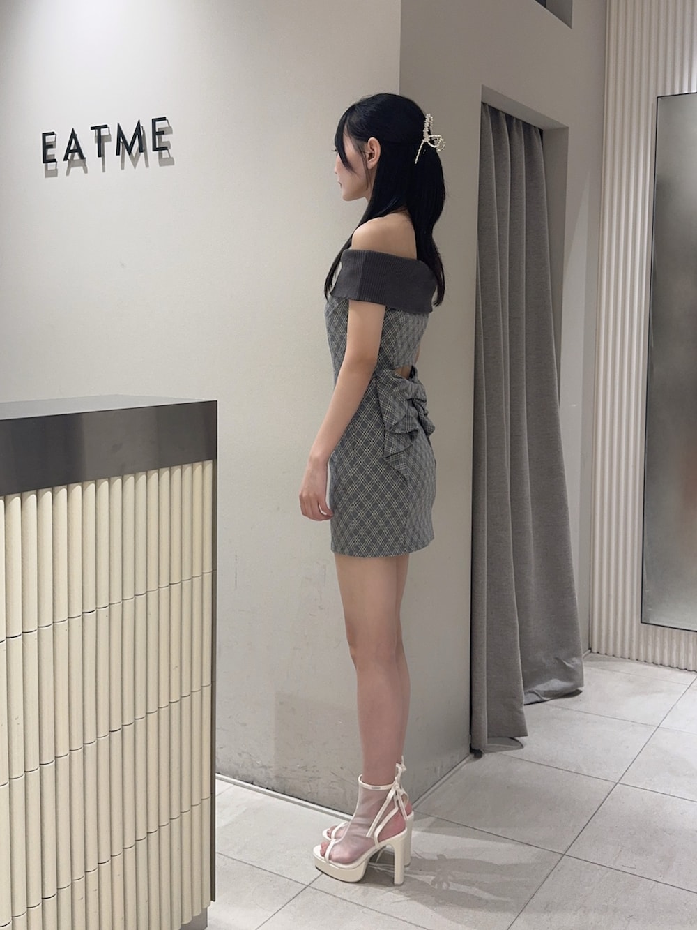グレー系のワンピース、ホワイト系のサンダル、ゴールド系のネックレスを着用したレディースの夏コーディネートの2枚目の写真