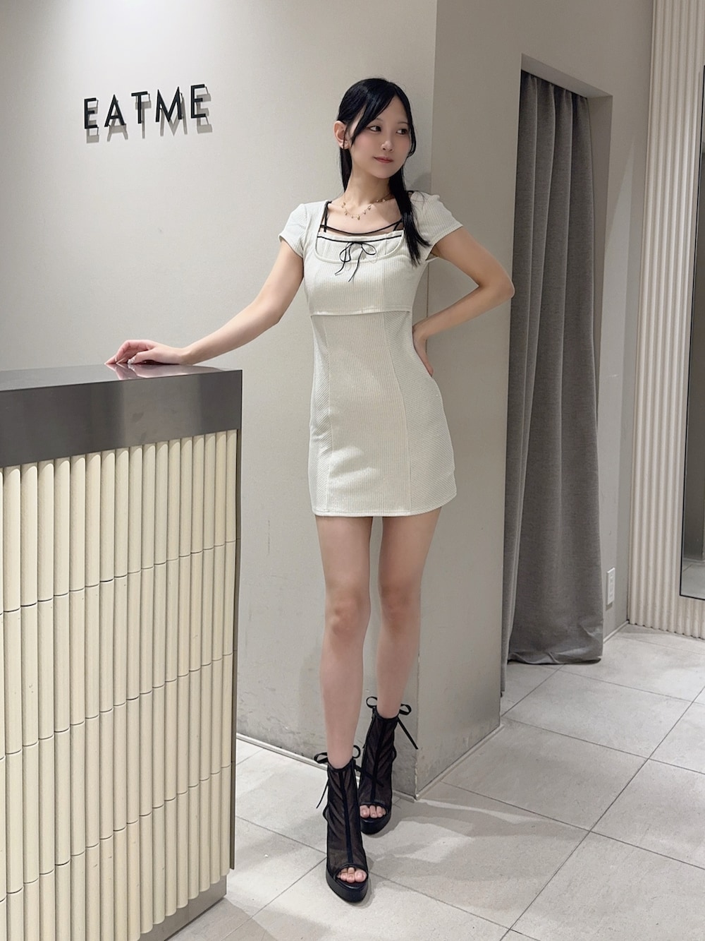 ホワイト系のワンピース、ブラック系のハンドバッグ、ブラック系のサンダルを着用したレディースの夏コーディネートの4枚目の写真