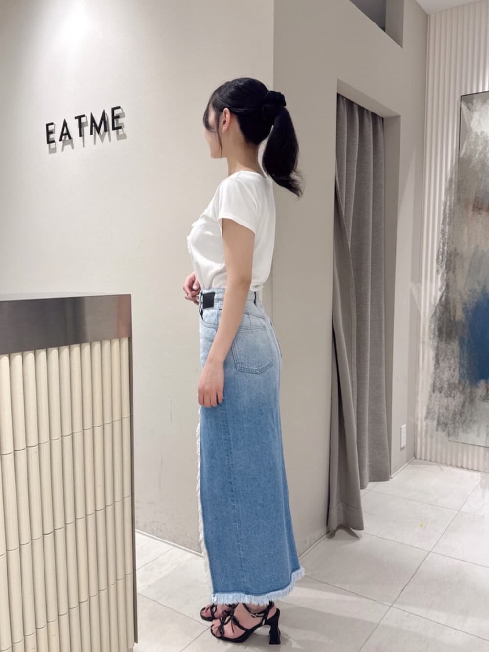 ブラック系のサンダル、ホワイト系のTシャツ/カットソー、ブルー系のデニムスカートを着用したレディースの夏コーディネートの2枚目の写真