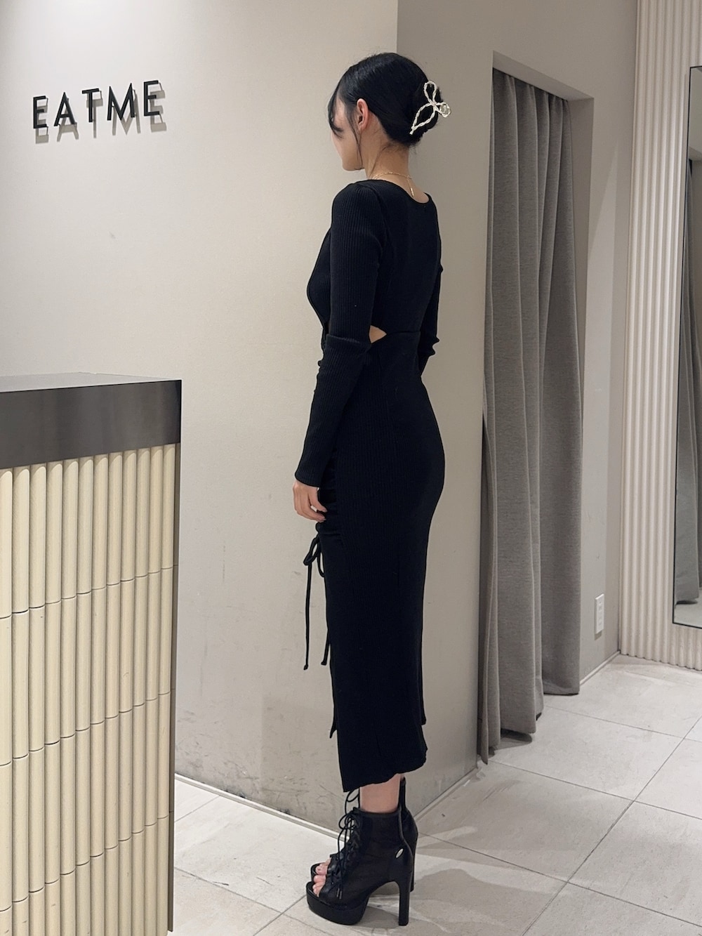 ブラック系のワンピース、ブラック系のブーツ、ゴールド系のネックレスを着用したレディースの冬コーディネートの3枚目の写真