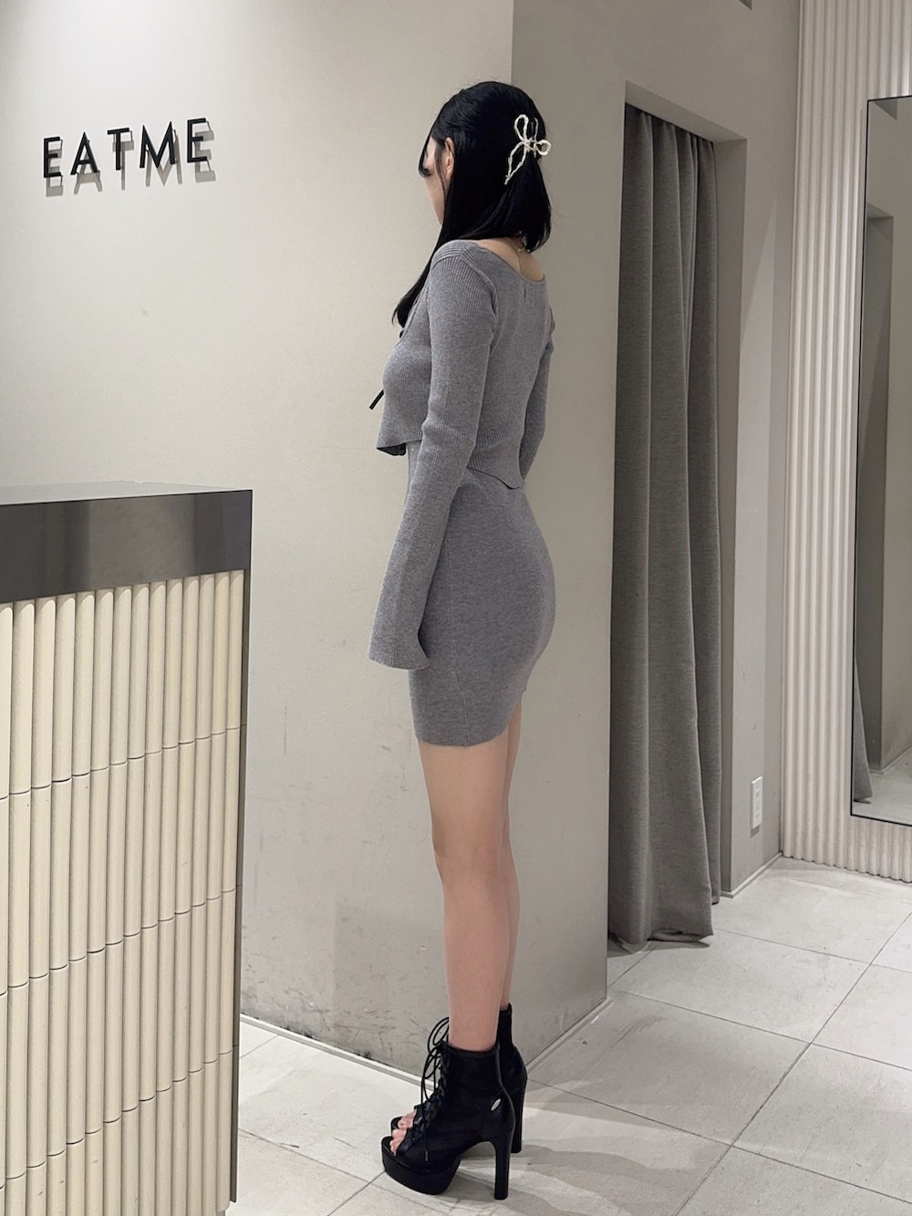 グレー系のワンピース、ブラック系のブーツ、ブラック系のハンドバッグを着用したレディースの冬コーディネートの3枚目の写真