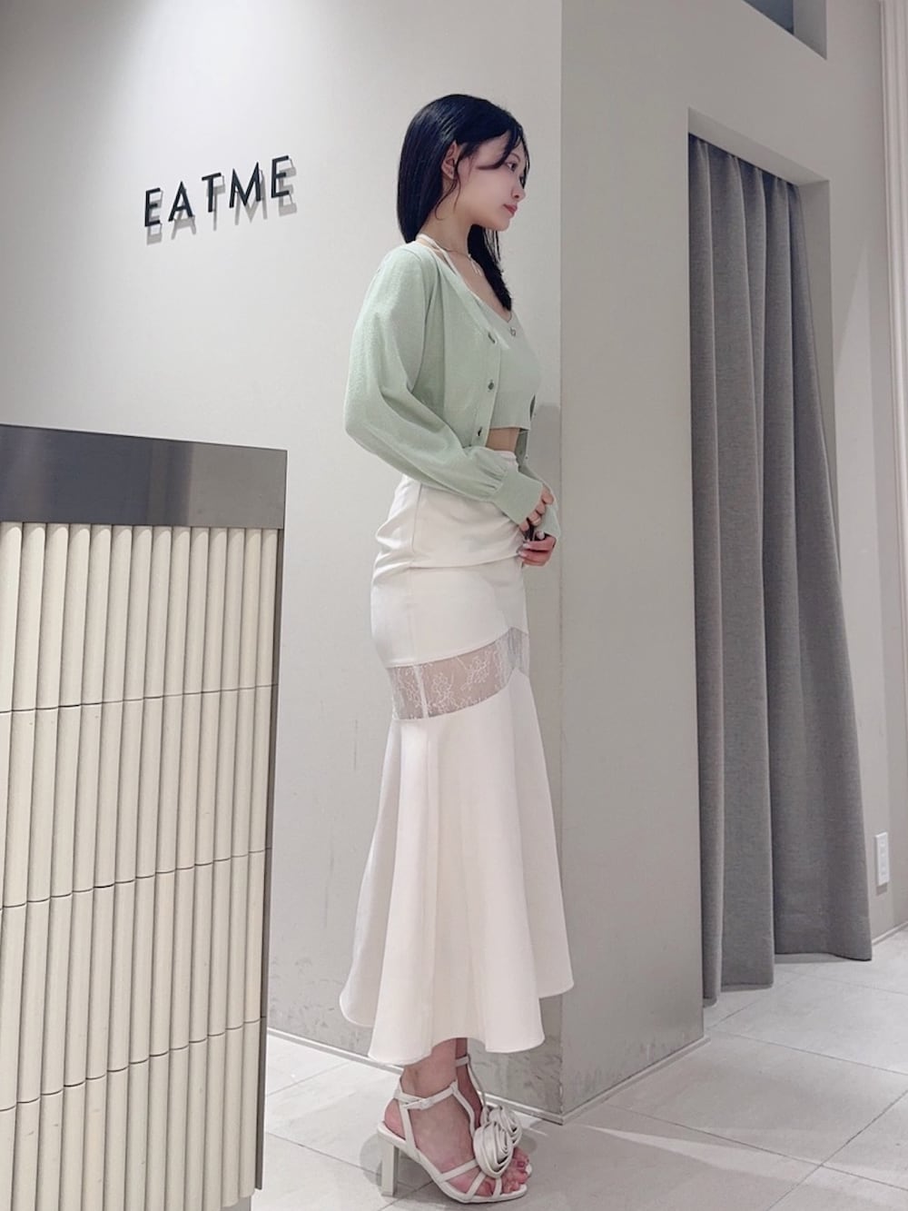 グリーン系のニット/セーター、ホワイト系のサンダル、グレー系のスカートを着用したレディースの夏コーディネートの3枚目の写真