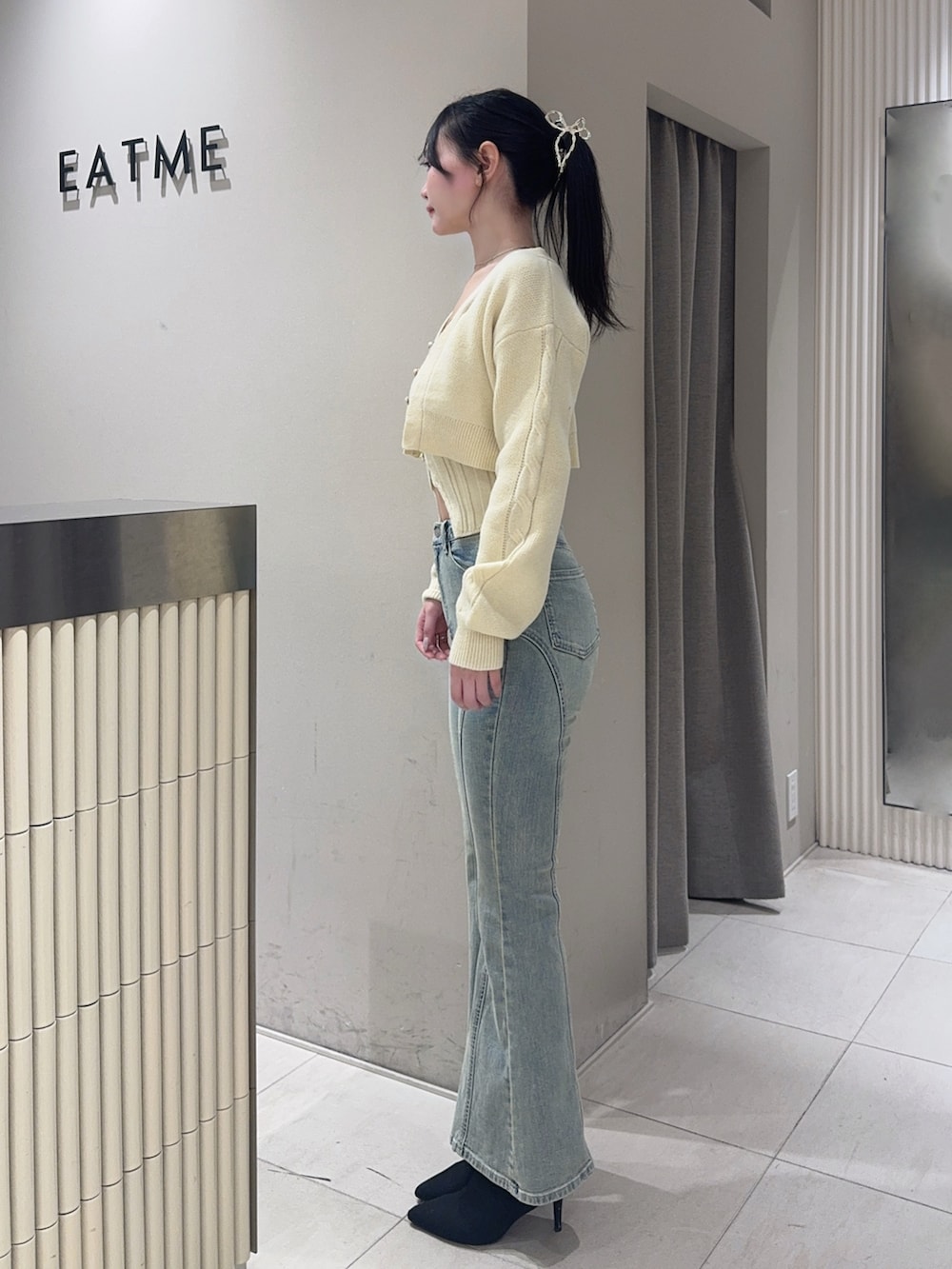 イエロー系のニット/セーター、ブルー系のデニムパンツ、ブラック系のブーツを着用したレディースの冬コーディネートの2枚目の写真