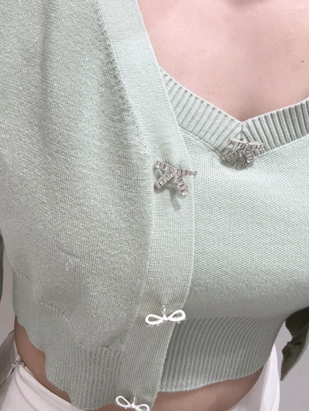 グリーン系のニット/セーター、ホワイト系のサンダル、グレー系のスカートを着用したレディースの夏コーディネートの6枚目の写真