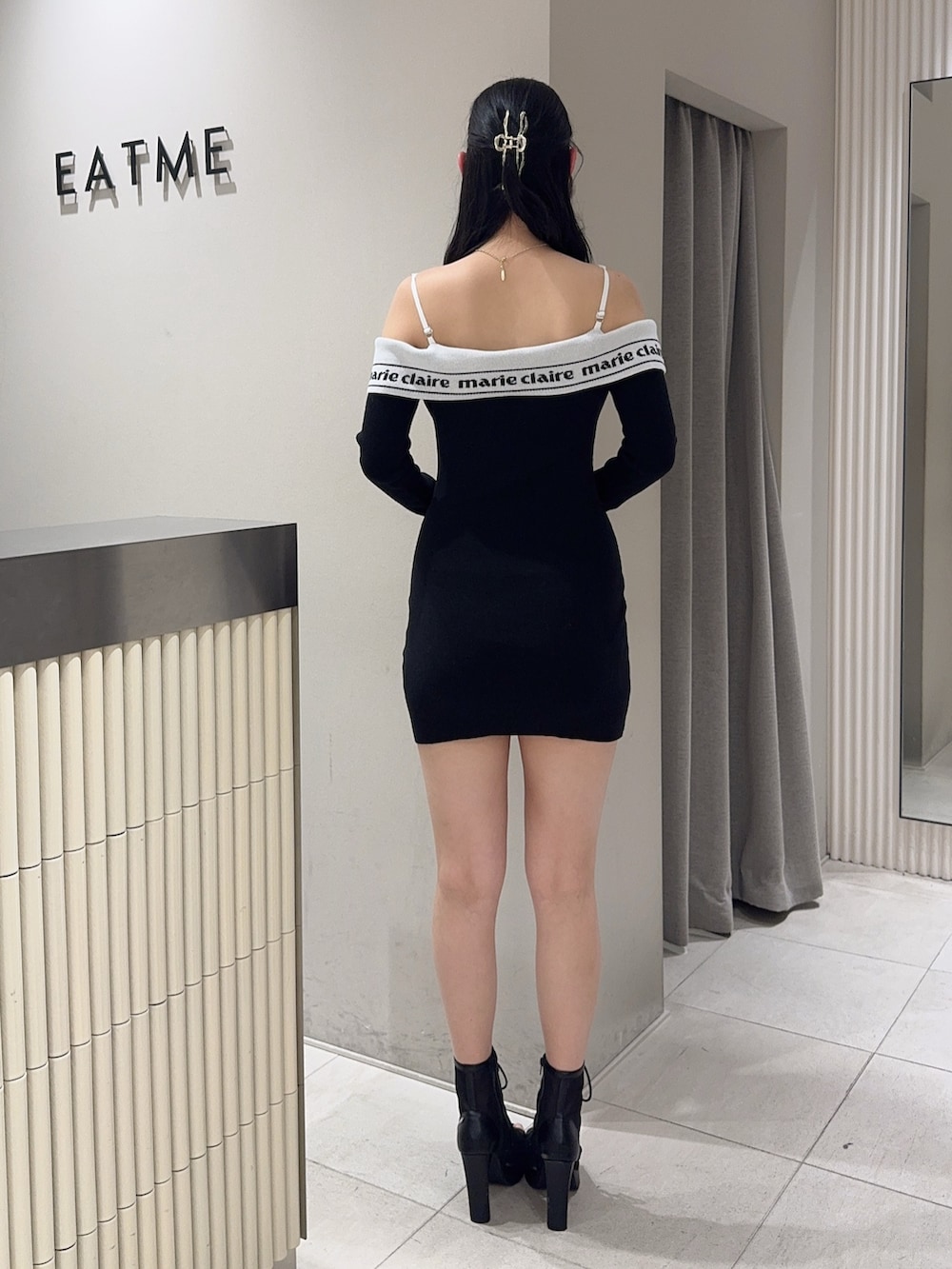 ブラック系のワンピース、ブラック系のハンドバッグ、ブラック系のブーツを着用したレディースの春コーディネートの3枚目の写真