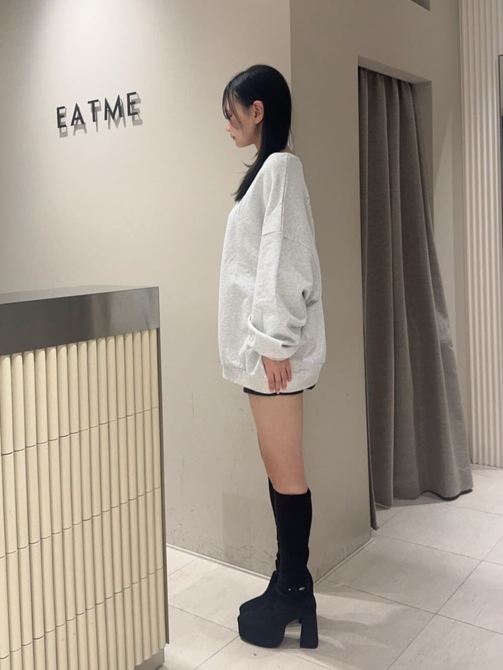 ブラック系のデニムスカート、ブラック系のブーツ、グレー系のスウェットを着用したレディースの秋コーディネートの2枚目の写真