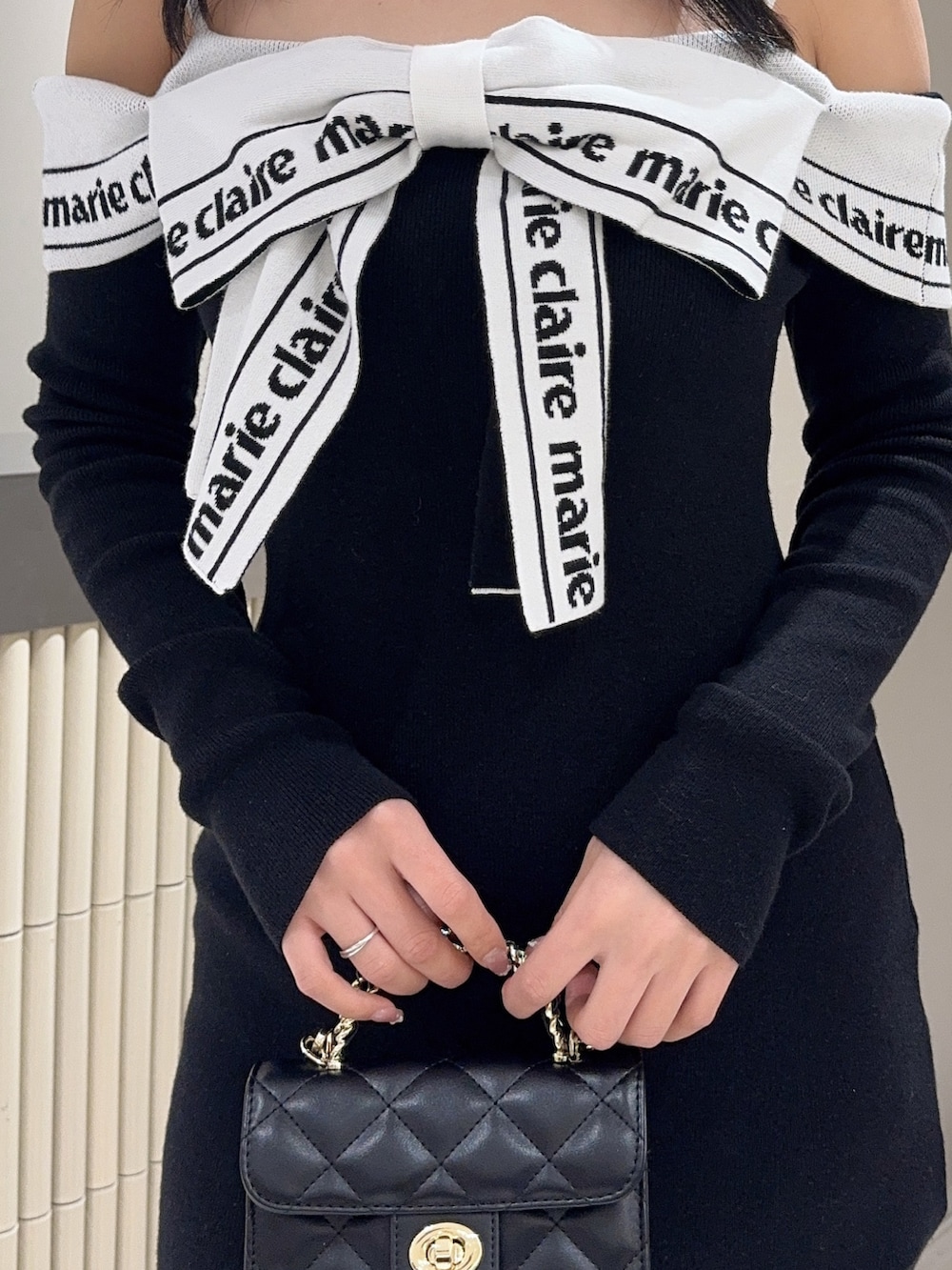 ブラック系のワンピース、ブラック系のハンドバッグ、ブラック系のブーツを着用したレディースの春コーディネートの5枚目の写真