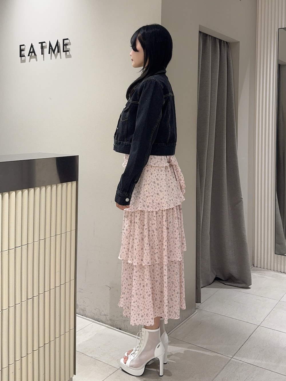 ピンク系のワンピース、ブラック系のデニムジャケット、ホワイト系のブーツを着用したレディースの春コーディネートの2枚目の写真