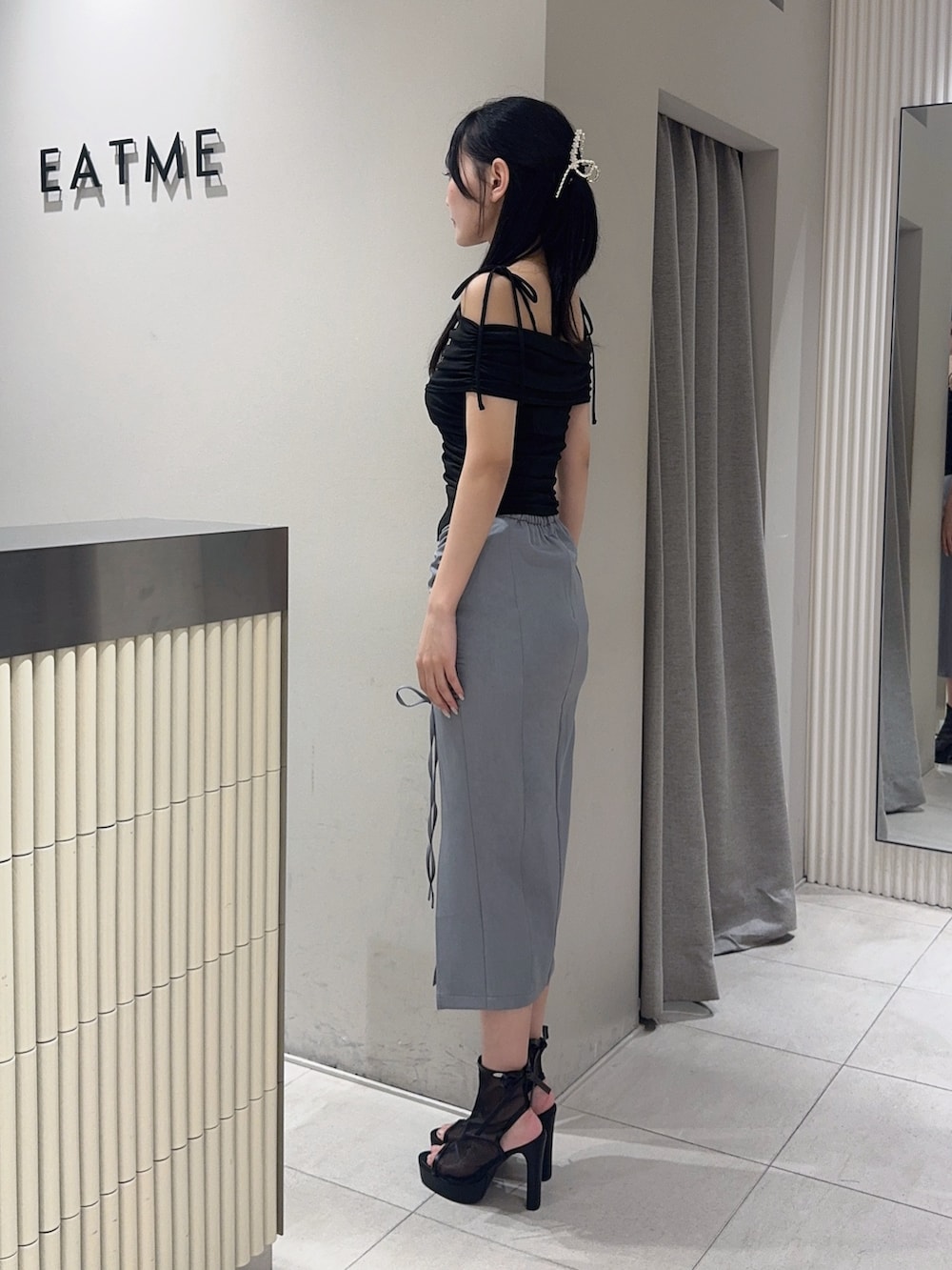 ブラック系のサンダル、グレー系のスカート、ブラック系のTシャツ/カットソーを着用したレディースの夏コーディネートの2枚目の写真