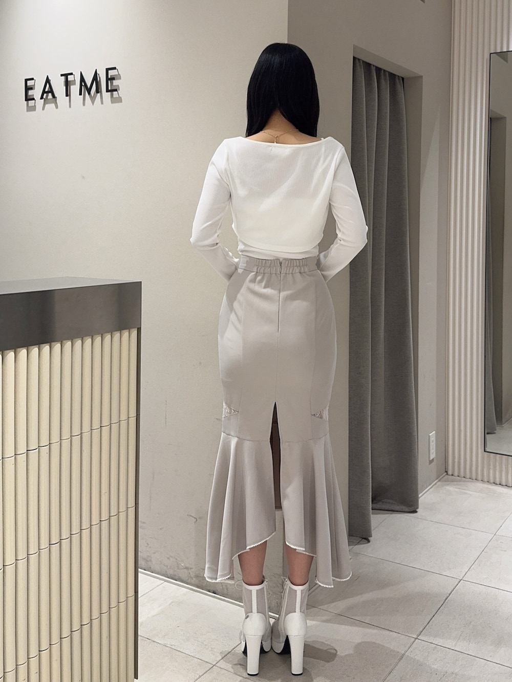 グレー系のスカート、ホワイト系のTシャツ/カットソー、ホワイト系のブーツを着用したレディースの春コーディネートの3枚目の写真