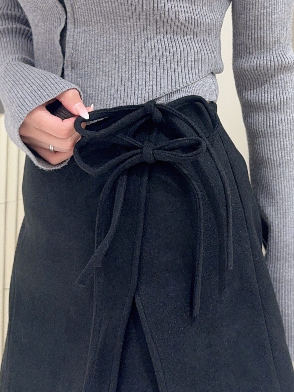 グレー系のニット/セーター、ブラック系のスカート、ブラック系のブーツを着用したレディースの秋コーディネートの5枚目の写真