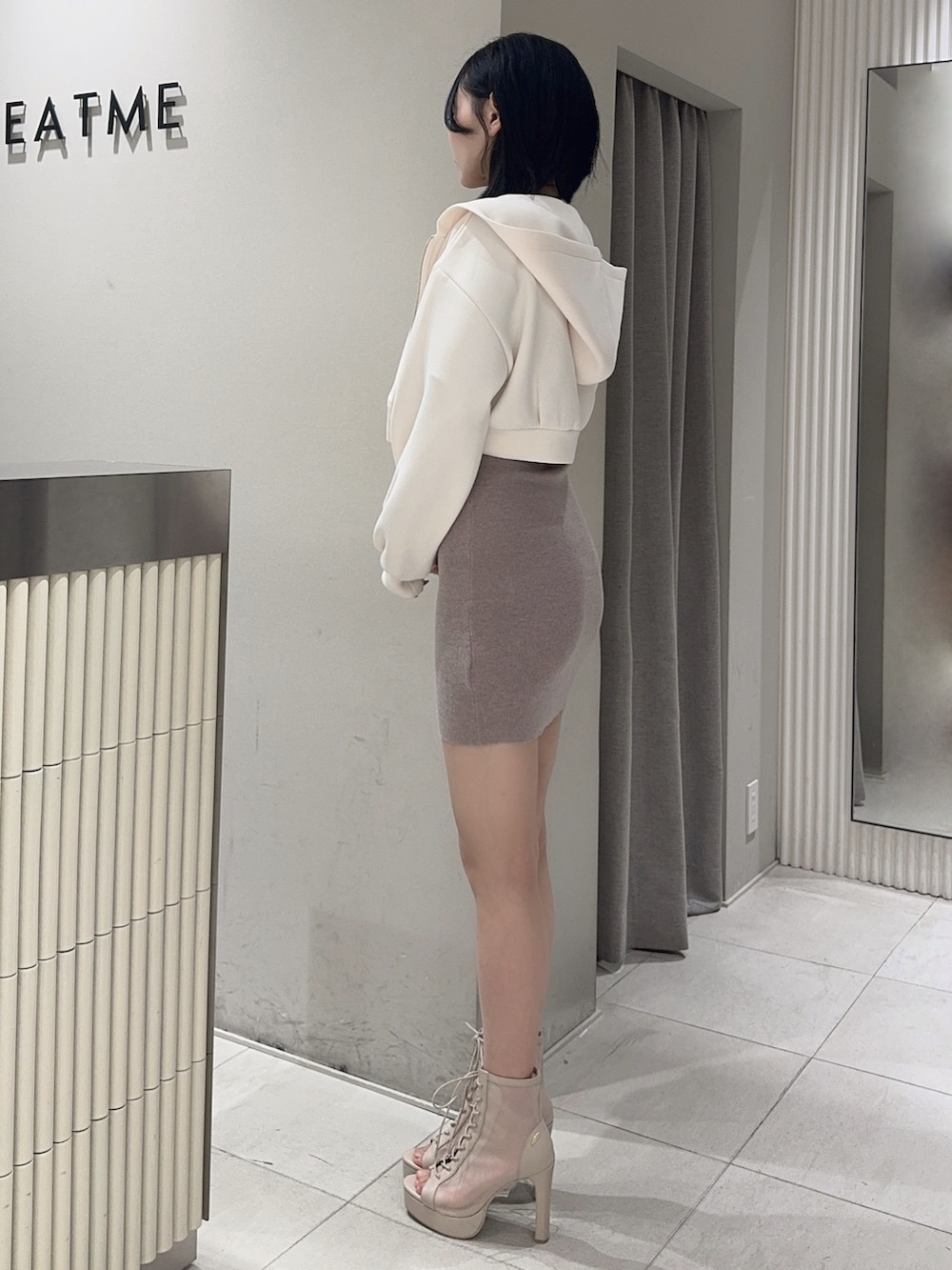 ベージュ系のワンピース、ホワイト系のパーカー、ベージュ系のブーツを着用したレディースの冬コーディネートの2枚目の写真