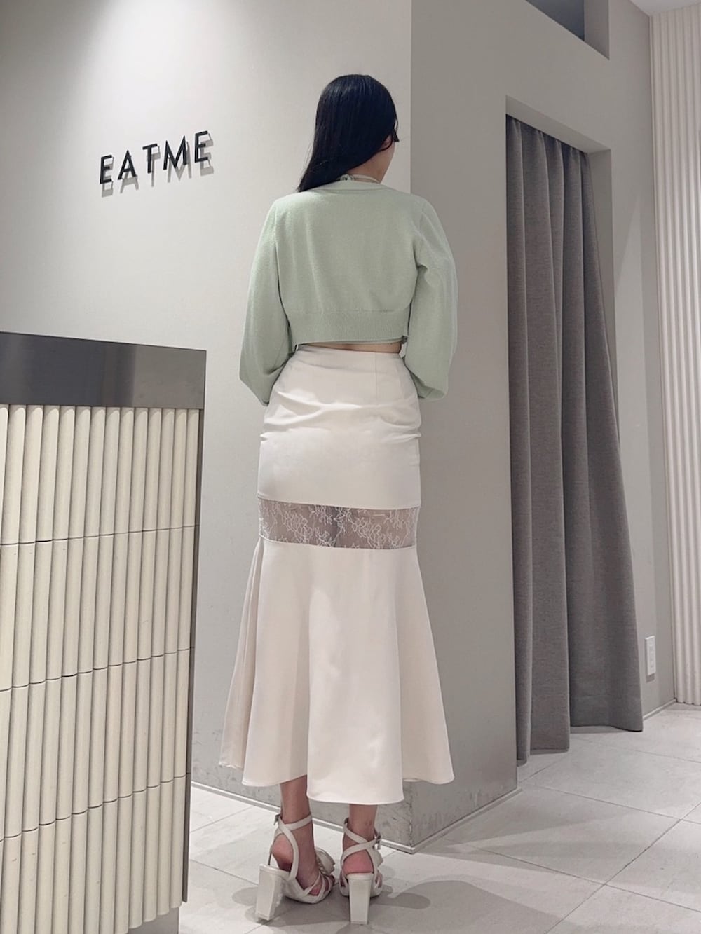 グリーン系のニット/セーター、ホワイト系のサンダル、グレー系のスカートを着用したレディースの夏コーディネートの4枚目の写真