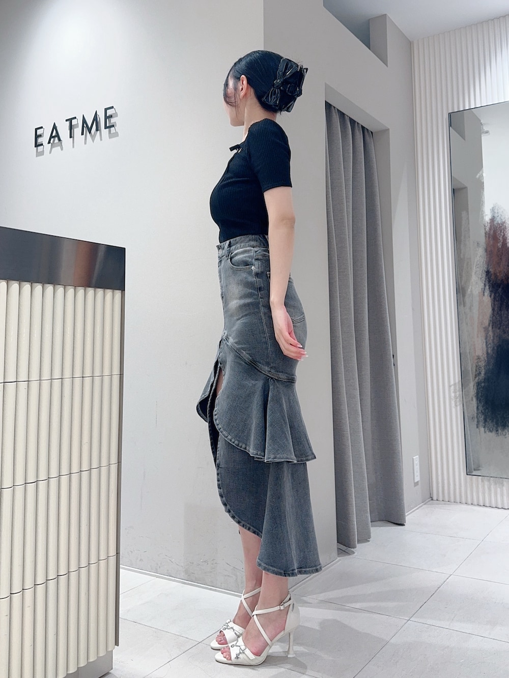 ブラック系のTシャツ/カットソー、ブラック系のデニムスカート、ホワイト系のサンダルを着用したレディースの夏コーディネートの2枚目の写真