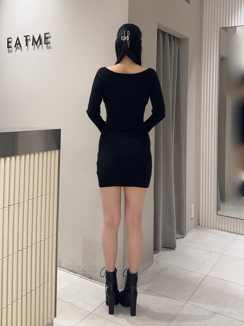 ブラック系のブーツ、ブラック系のワンピース、ゴールド系のバレッタ/ヘアクリップを着用したレディースの冬コーディネートの4枚目の写真