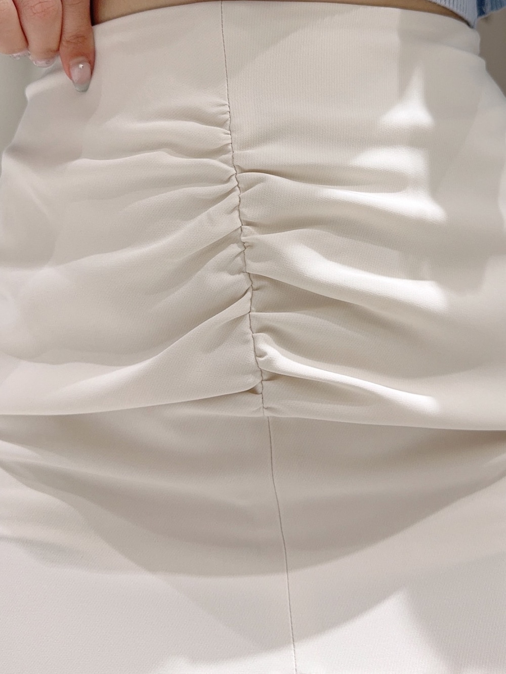 グリーン系のニット/セーター、ホワイト系のサンダル、グレー系のスカートを着用したレディースの夏コーディネートの7枚目の写真