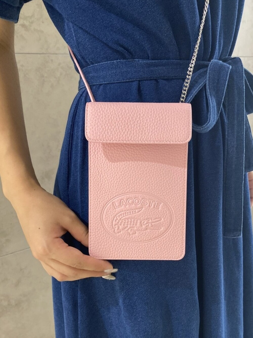 ブルー系のワンピース、ピンク系のショルダーバッグ、ホワイト系のスニーカーを着用したレディースの春コーディネートの4枚目の写真