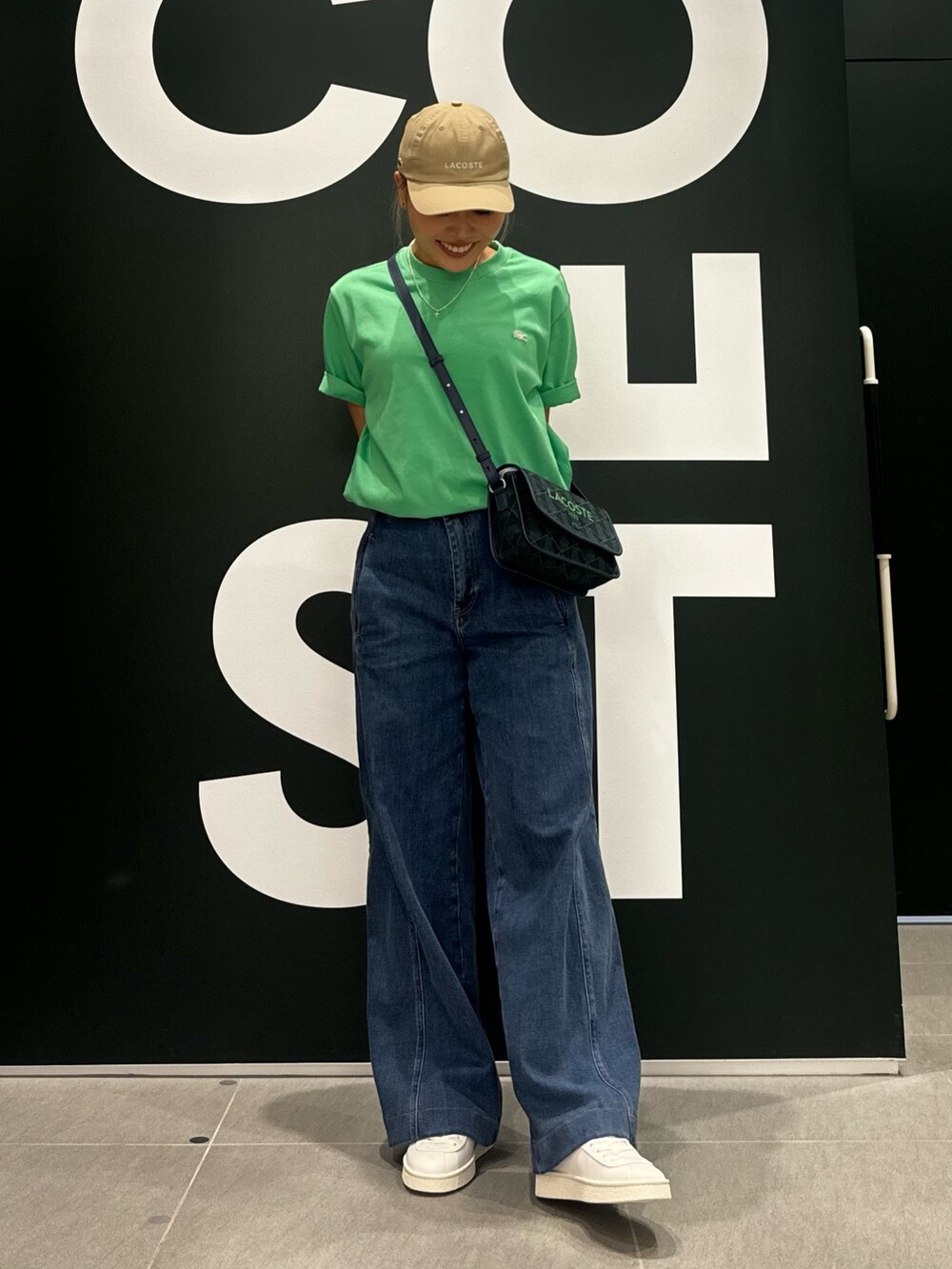 グリーン系のTシャツ/カットソー、ブルー系のデニムパンツ、ホワイト系のスニーカーを着用したレディースの夏コーディネートの2枚目の写真