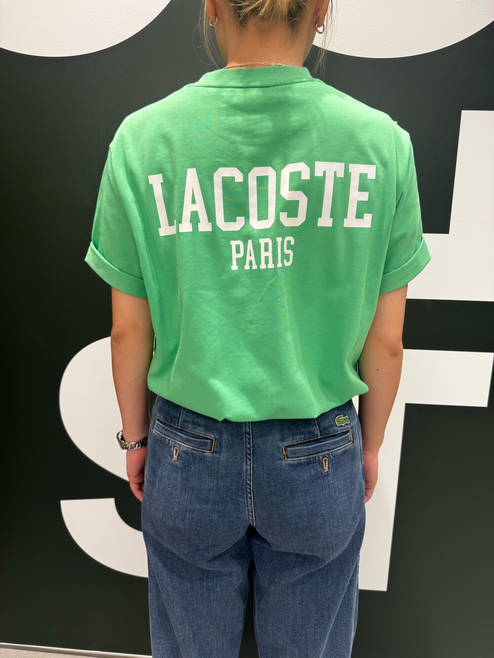 グリーン系のTシャツ/カットソー、ブルー系のデニムパンツ、ホワイト系のスニーカーを着用したレディースの夏コーディネートの3枚目の写真