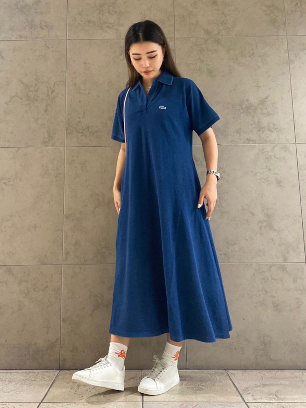 ブルー系のワンピース、ピンク系のショルダーバッグ、ホワイト系のスニーカーを着用したレディースの春コーディネートの2枚目の写真