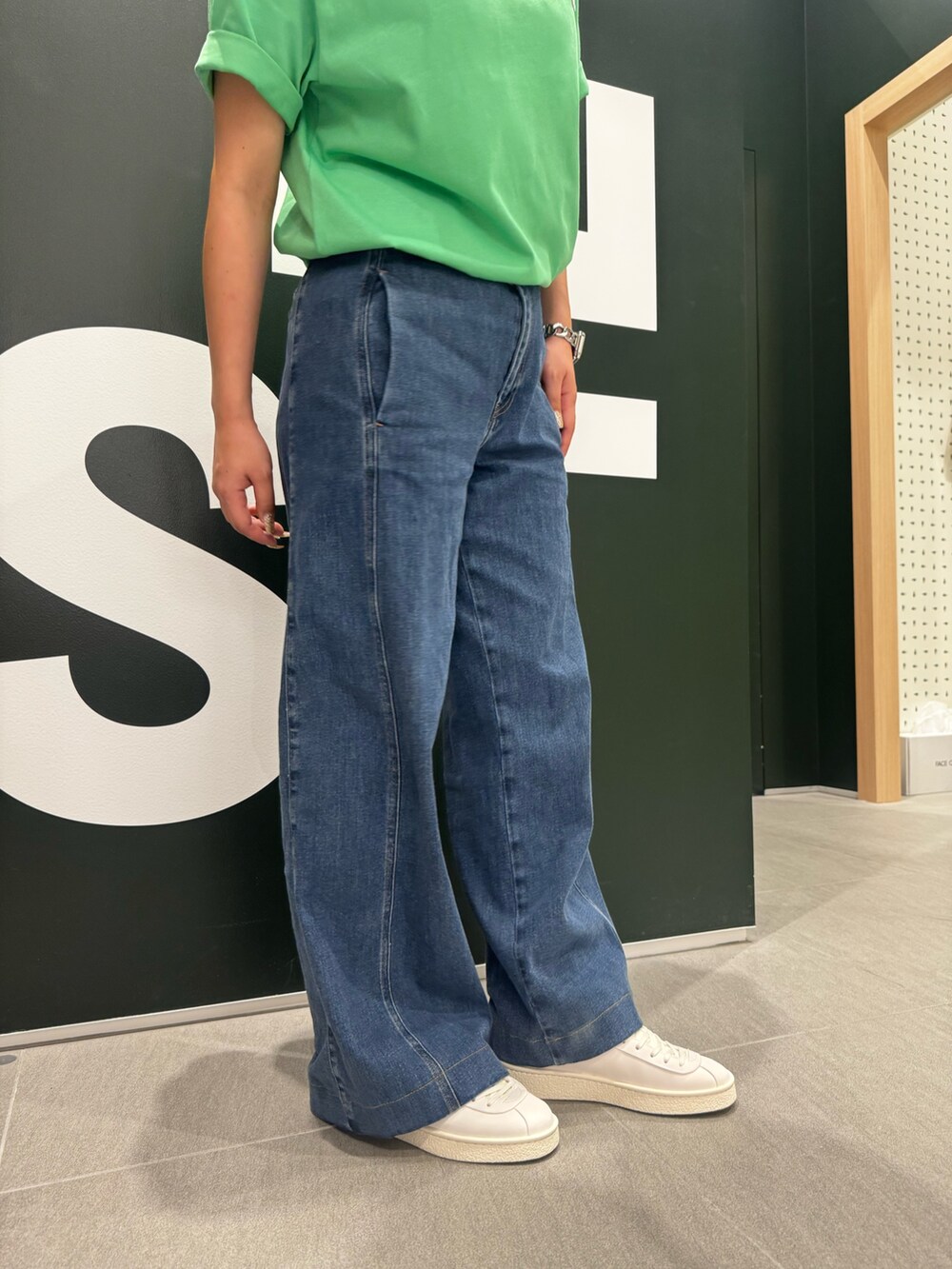 グリーン系のTシャツ/カットソー、ブルー系のデニムパンツ、ホワイト系のスニーカーを着用したレディースの夏コーディネートの4枚目の写真