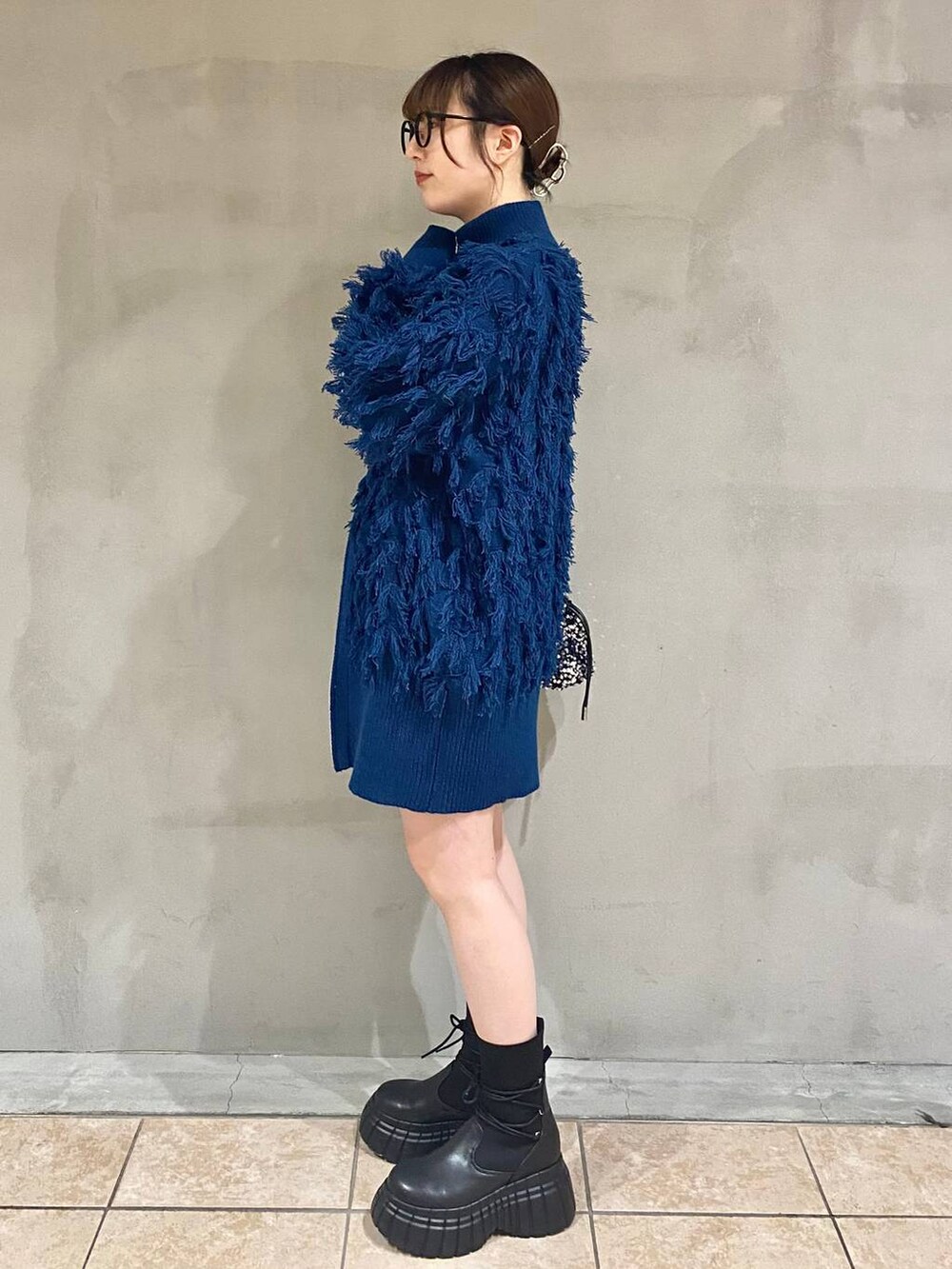 ブラック系のその他パンツ、ブラック系のブーツ、ブルー系のニット/セーターを着用したレディースの冬コーディネートの2枚目の写真