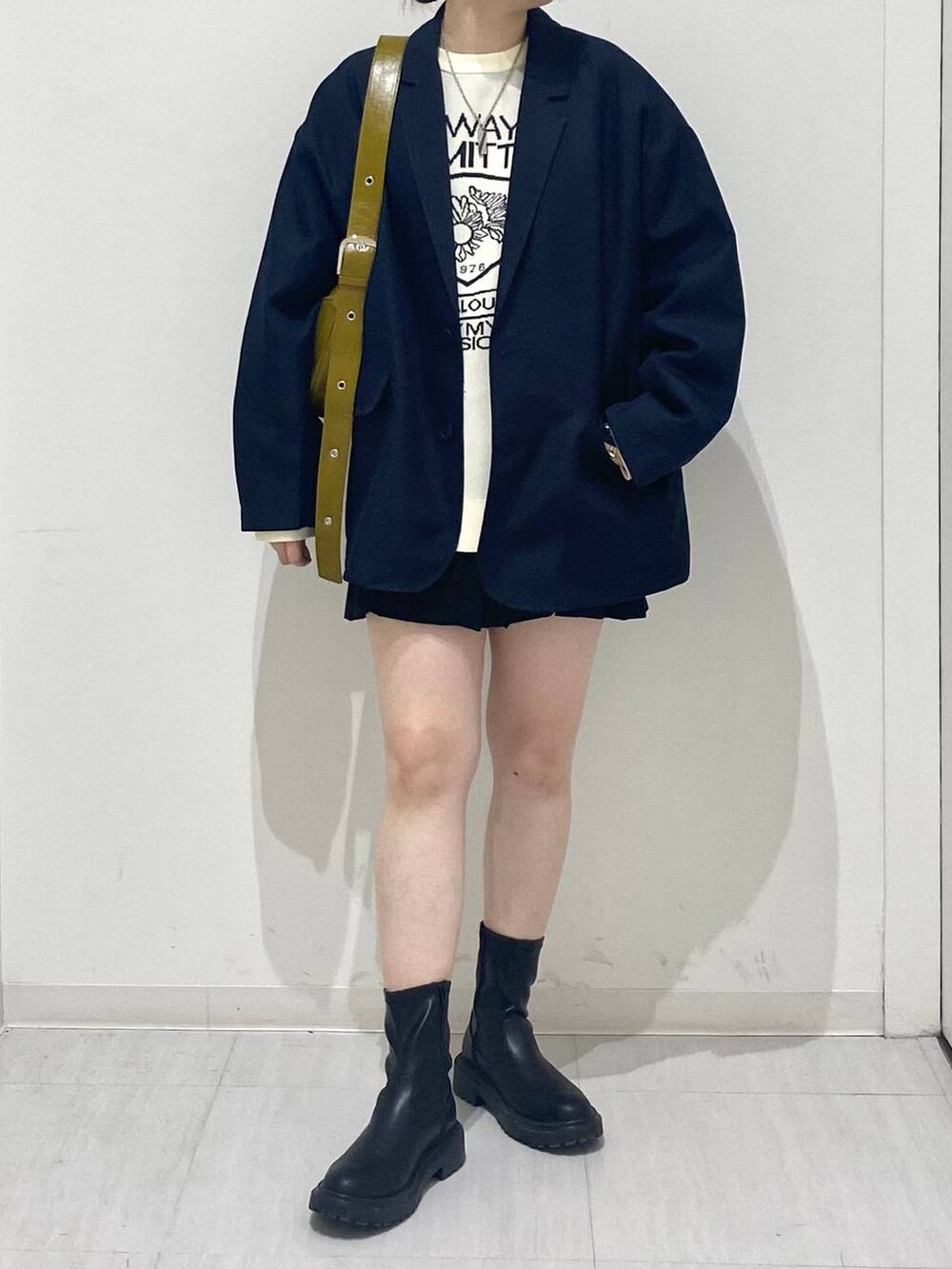 ブルー系のテーラードジャケット、ホワイト系のニット/セーター、イエロー系のショルダーバッグを着用したレディースの冬コーディネートの5枚目の写真