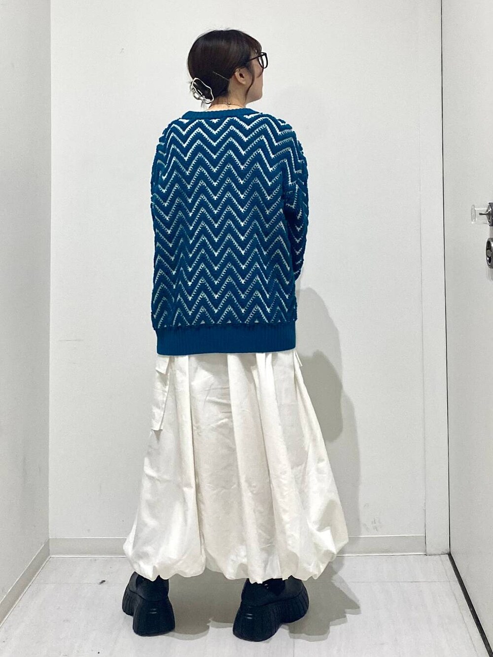 ブラック系のブーツ、ホワイト系のスカート、ブルー系のニット/セーターを着用したレディースの冬コーディネートの3枚目の写真