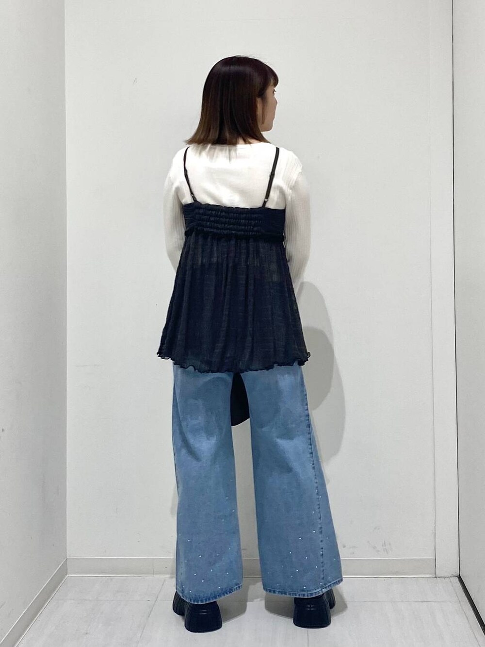 ホワイト系のニット/セーター、ブルー系のデニムパンツ、グレー系のキャミソールを着用したレディースの冬コーディネートの3枚目の写真