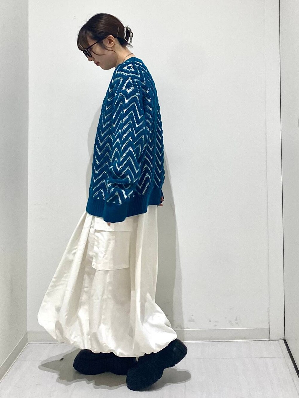 ブラック系のブーツ、ホワイト系のスカート、ブルー系のニット/セーターを着用したレディースの冬コーディネートの2枚目の写真