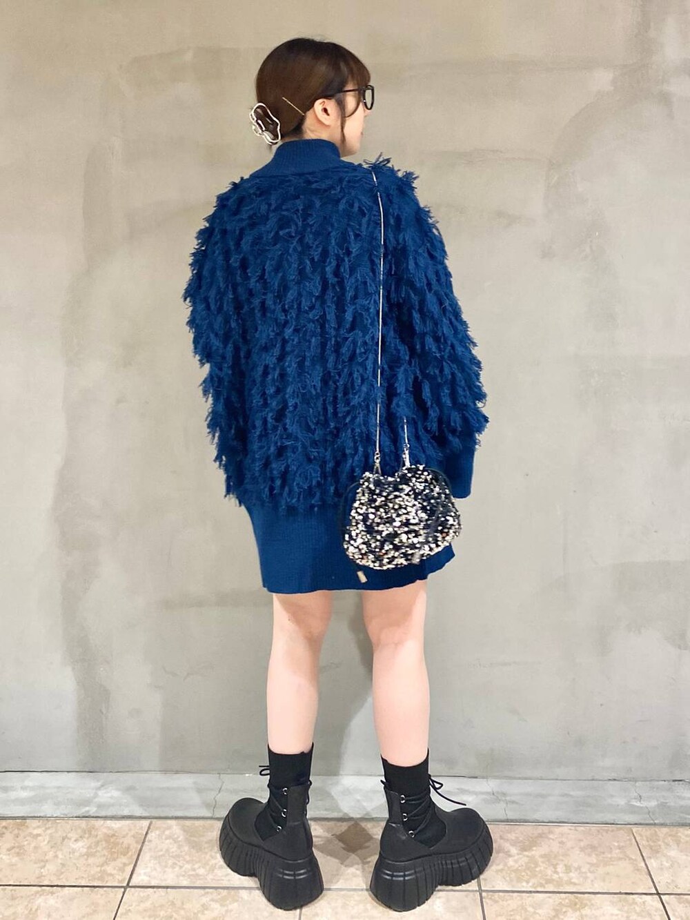 ブラック系のその他パンツ、ブラック系のブーツ、ブルー系のニット/セーターを着用したレディースの冬コーディネートの3枚目の写真