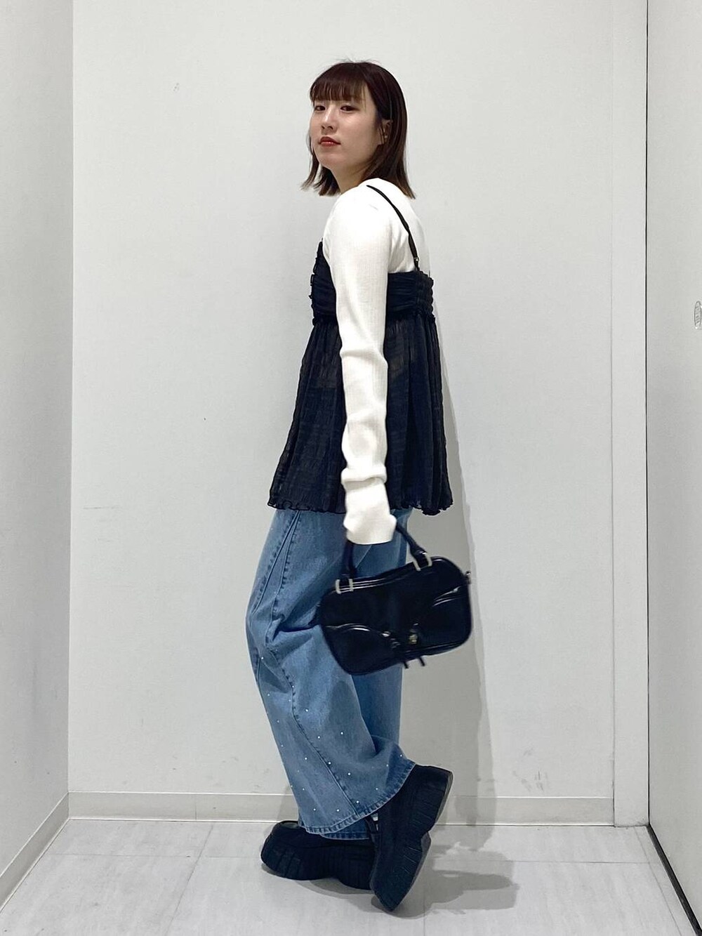 ホワイト系のニット/セーター、ブルー系のデニムパンツ、グレー系のキャミソールを着用したレディースの冬コーディネートの2枚目の写真