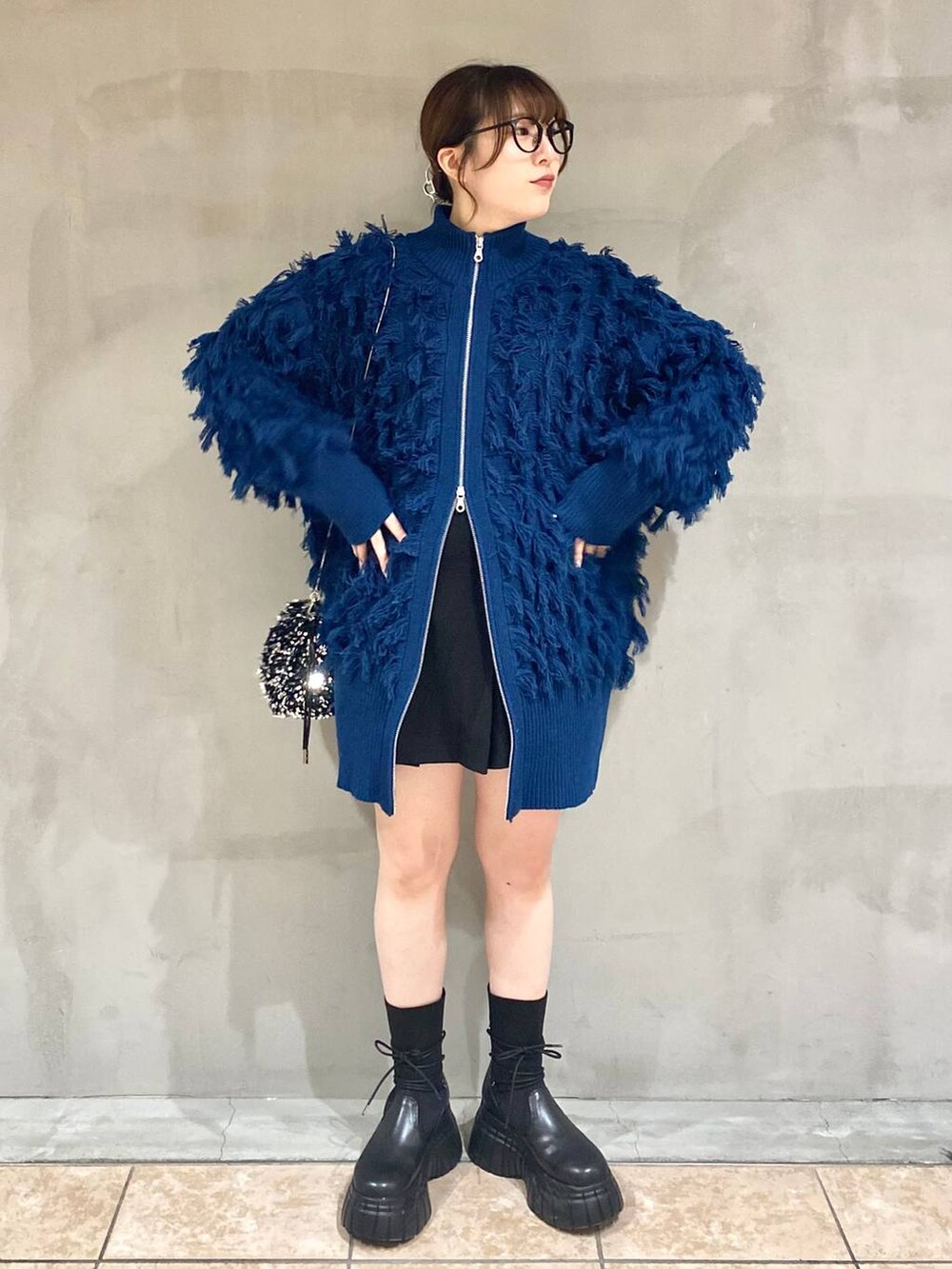 ブラック系のその他パンツ、ブラック系のブーツ、ブルー系のニット/セーターを着用したレディースの冬コーディネートの6枚目の写真