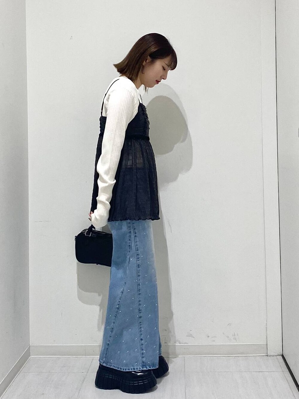 ホワイト系のニット/セーター、ブルー系のデニムパンツ、グレー系のキャミソールを着用したレディースの冬コーディネートの4枚目の写真