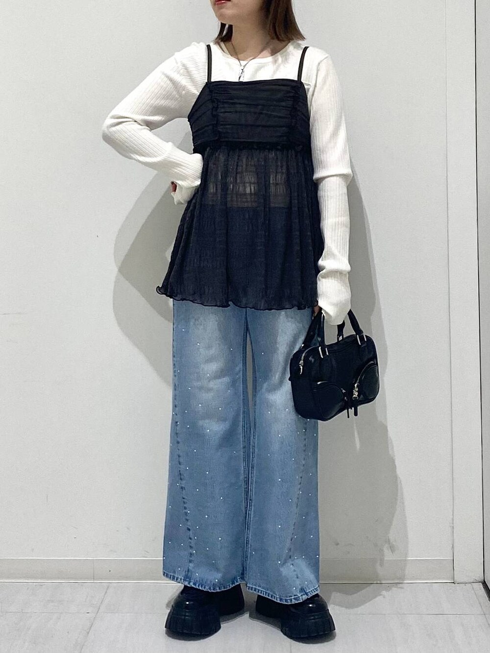 ホワイト系のニット/セーター、ブルー系のデニムパンツ、グレー系のキャミソールを着用したレディースの冬コーディネートの5枚目の写真