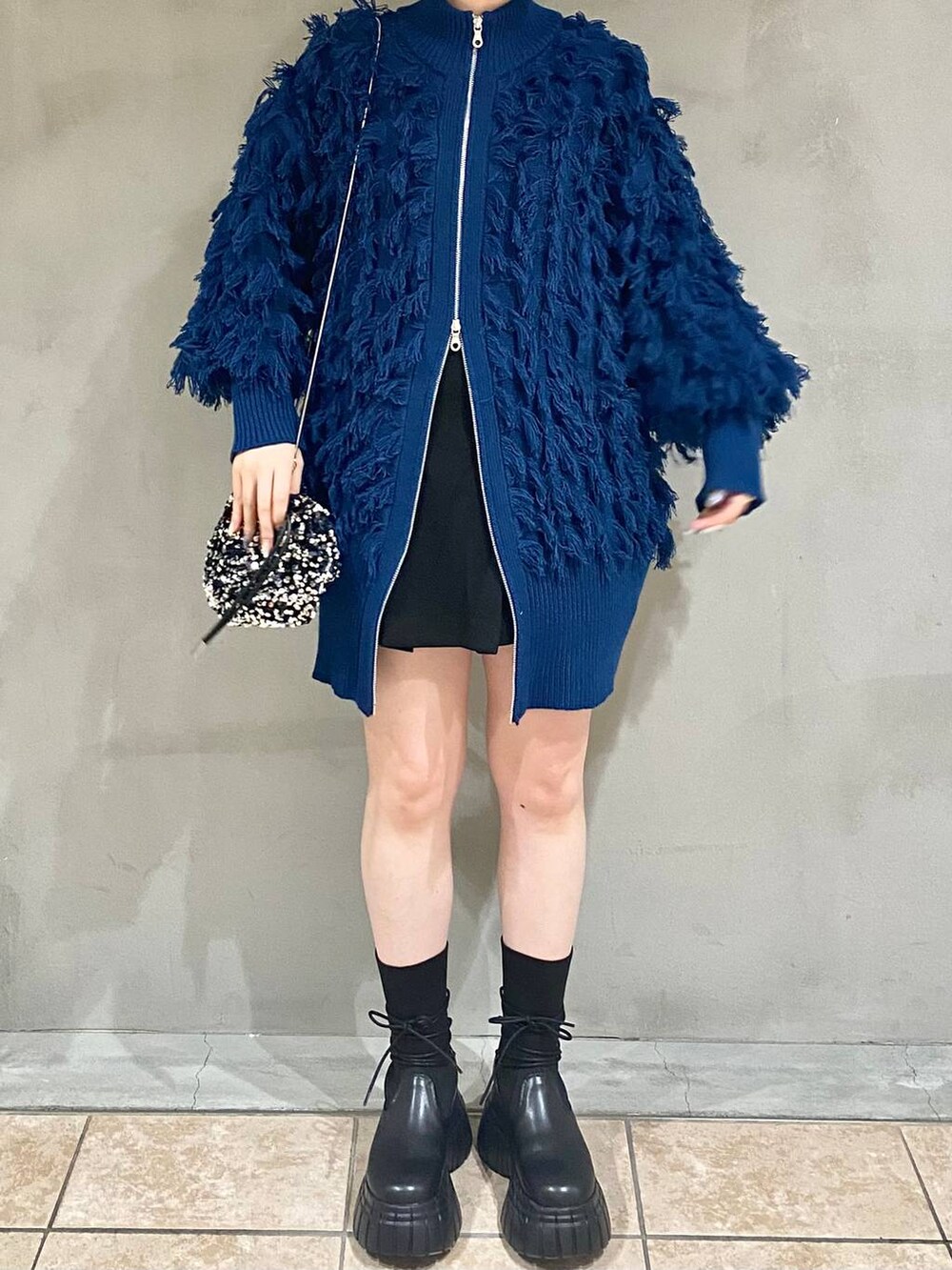 ブラック系のその他パンツ、ブラック系のブーツ、ブルー系のニット/セーターを着用したレディースの冬コーディネートの5枚目の写真