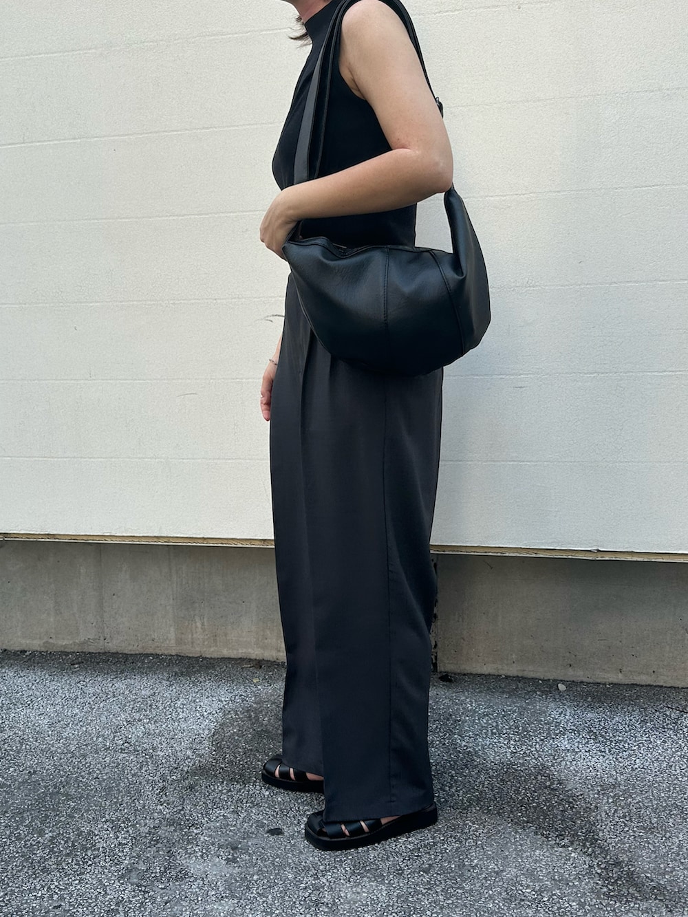 グレー系のスラックス、ブラック系のサンダル、ブラック系のトップスを着用したレディースの夏コーディネートの2枚目の写真